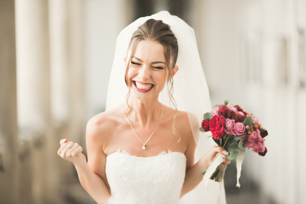 Luxury wedding bride, girl posing and smiling with bouquet of roses.