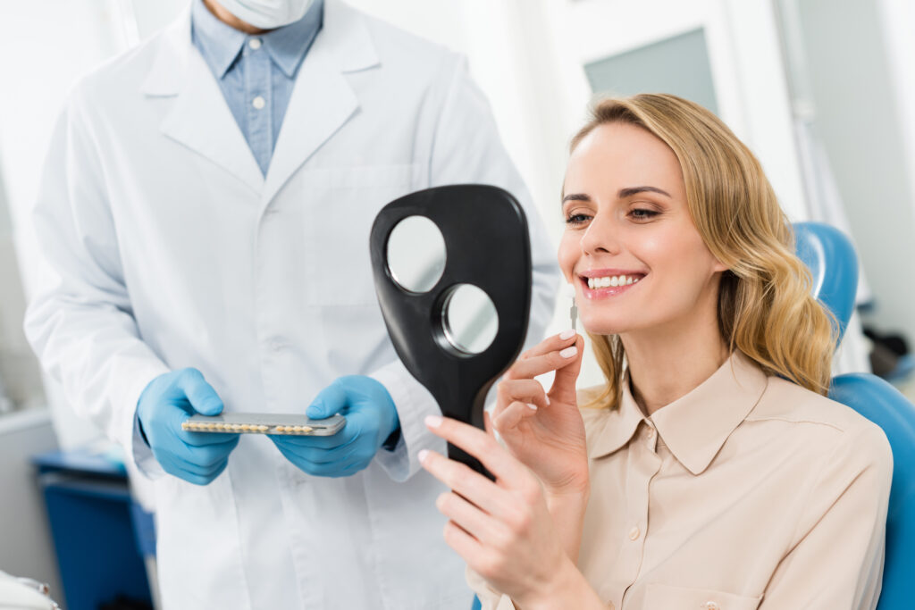 Woman choosing a dental implant looking in the mirror in a modern dental care clinic