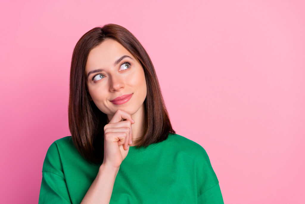 Photo of young funny attractive woman touch chin, thinking and looking up to empty space, isolated on pink colour background.