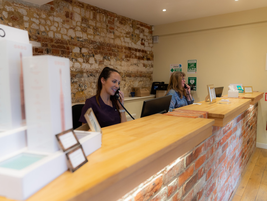 two receptionists on front of desk answering phone calls at barn dental clinic