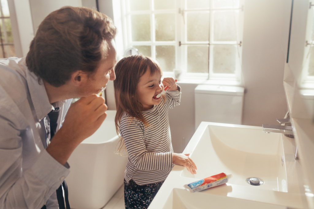 child and parent brushing teeth together